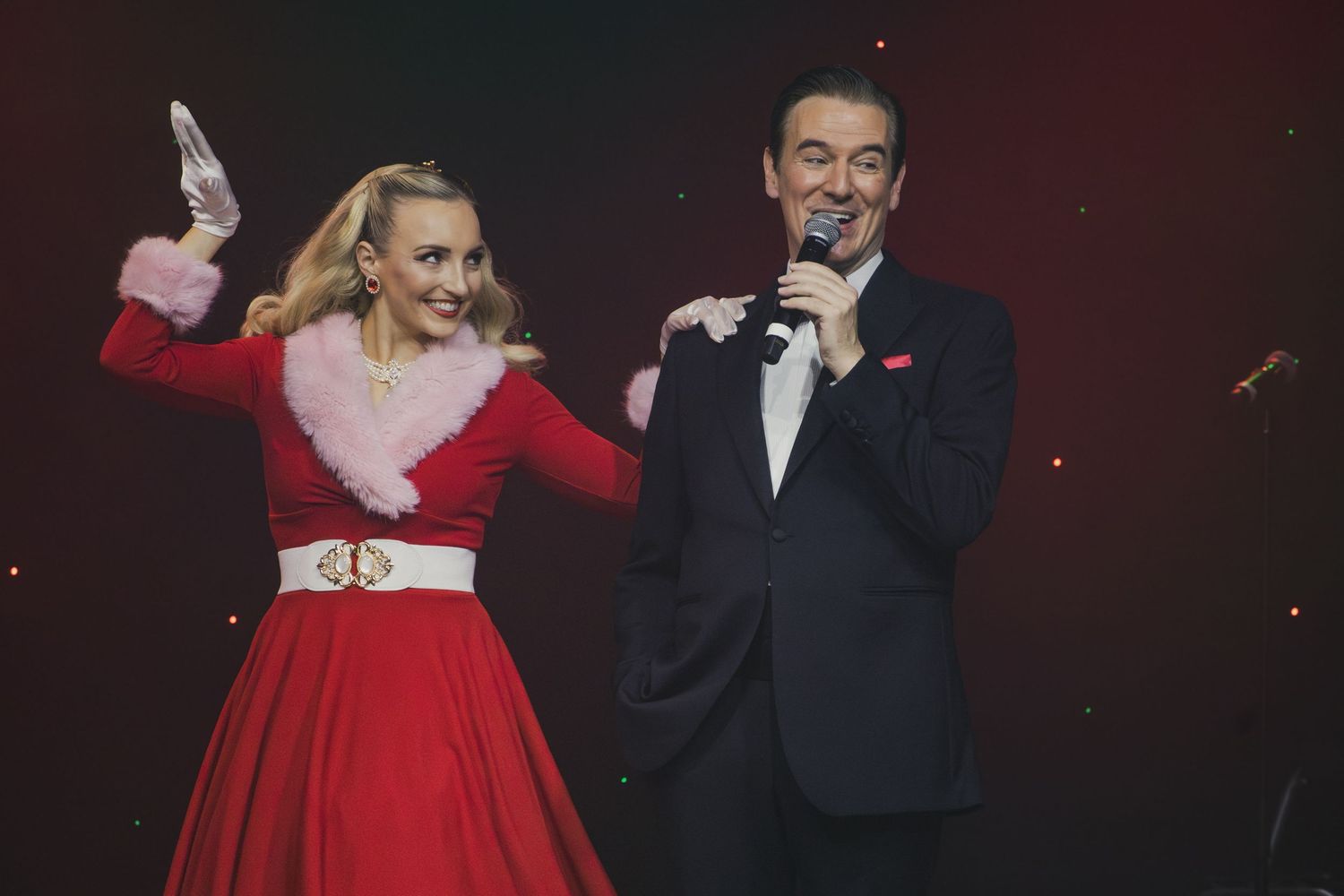 Performers in elegant attire sing together during an emotional stage performance.