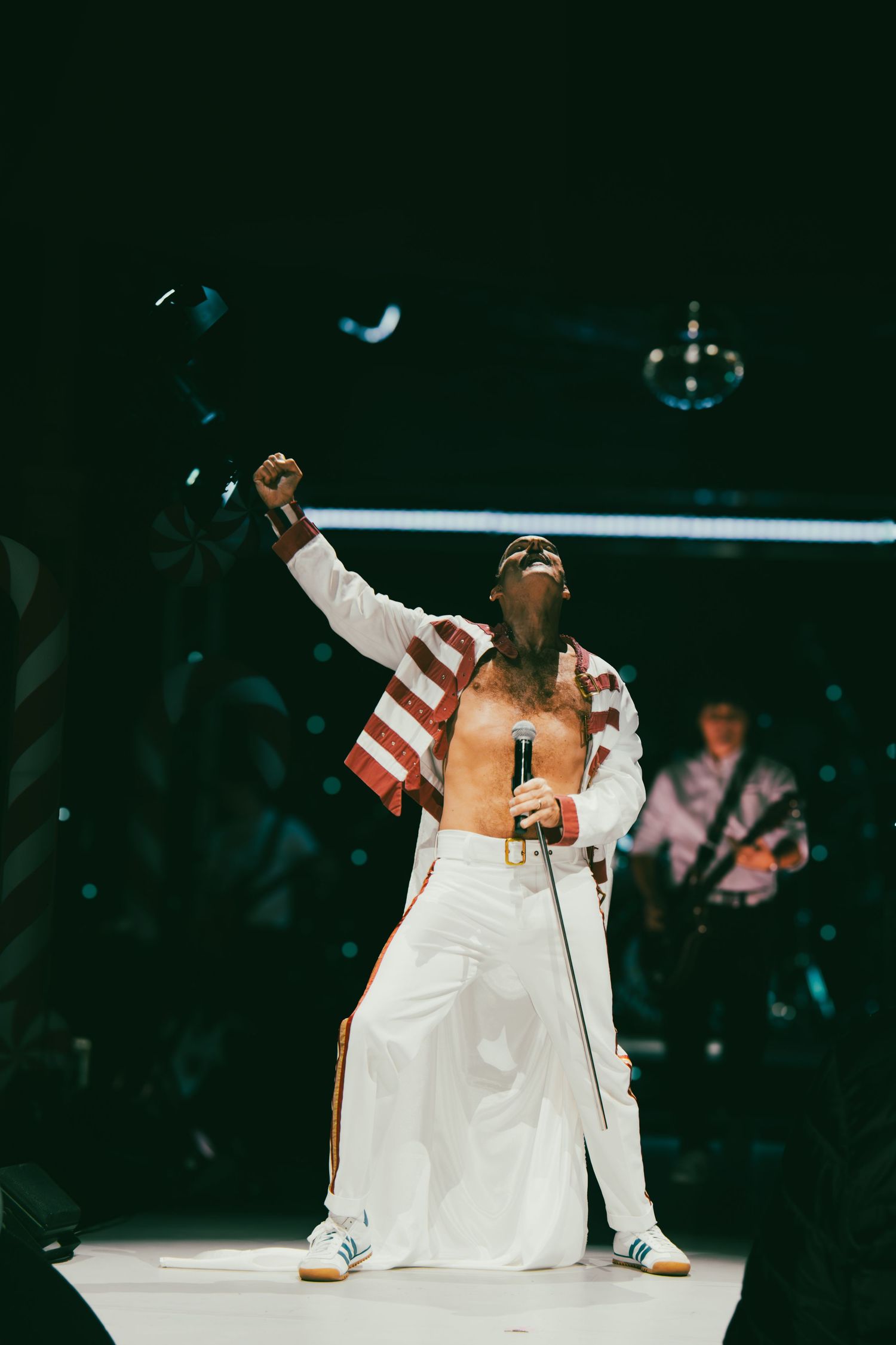 Performers in white outfits dance energetically on stage during live entertainment show.