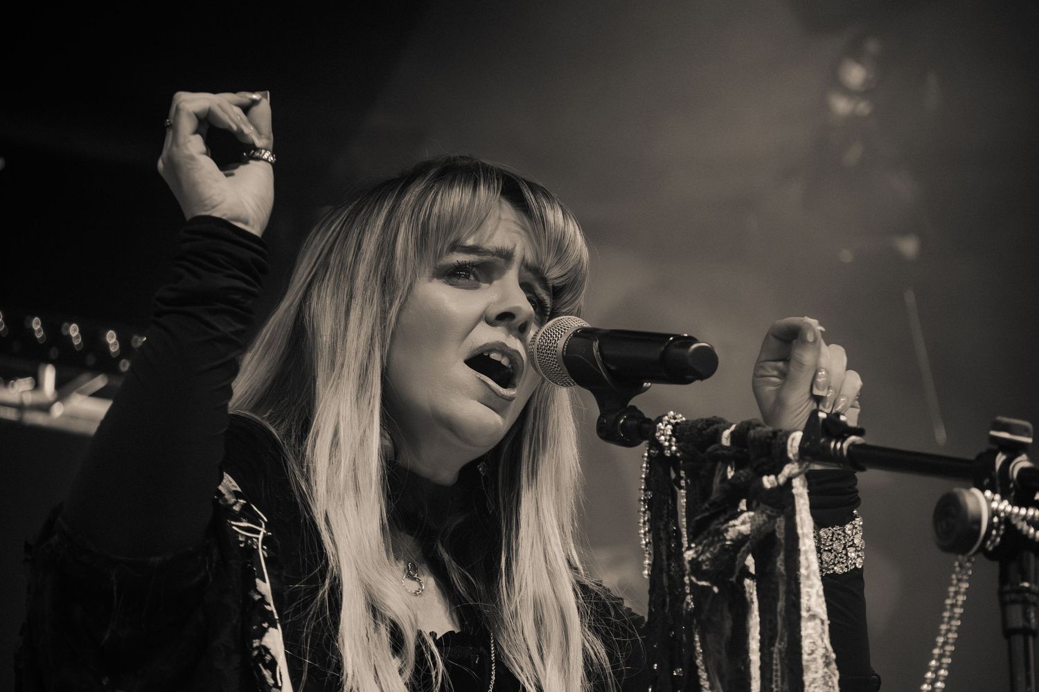 A singer performs passionately on stage in black and white, holding a microphone with dramatic lighting.