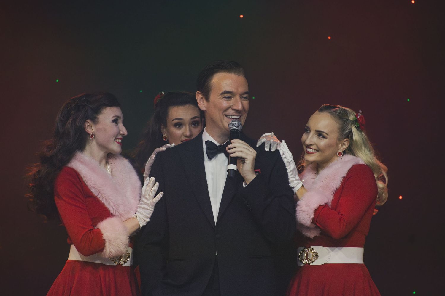 Festive stage show featuring performers in formal wear and holiday costumes.