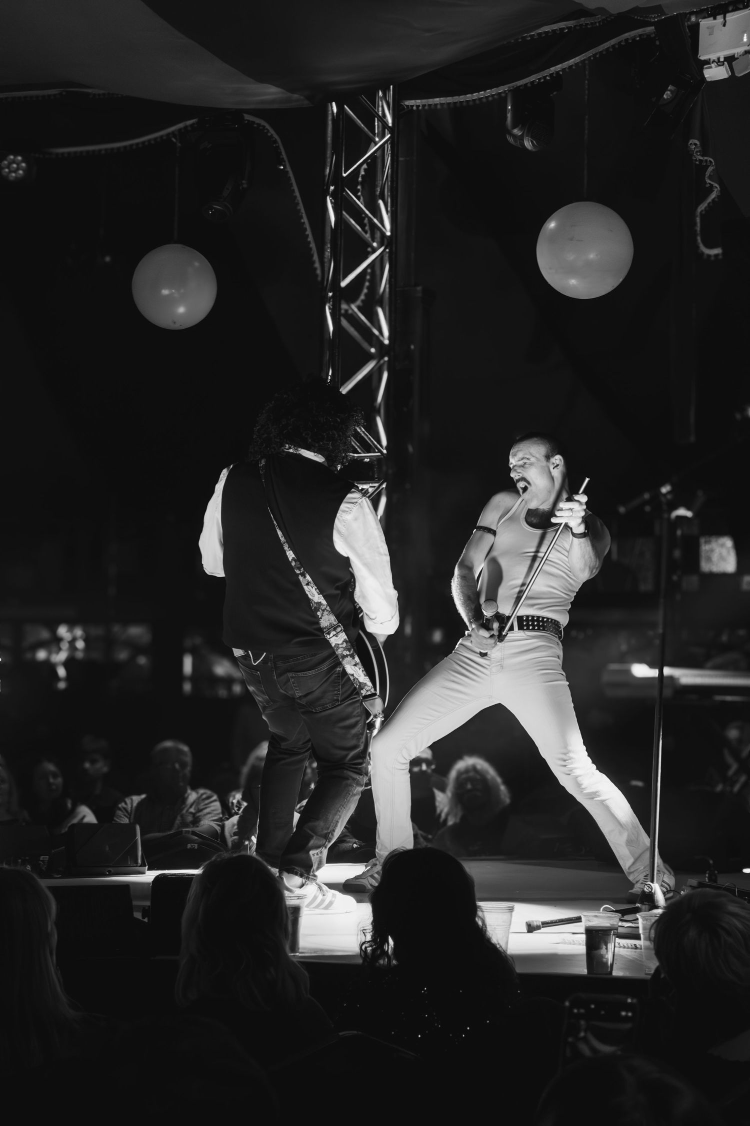 Silhouetted performers on stage create dynamic poses during a dramatic black and white performance.