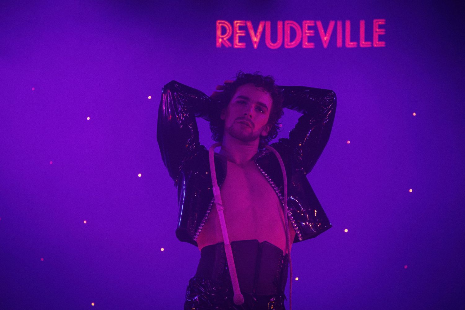 Purple-lit stage performance with Revudeville signage visible in background.
