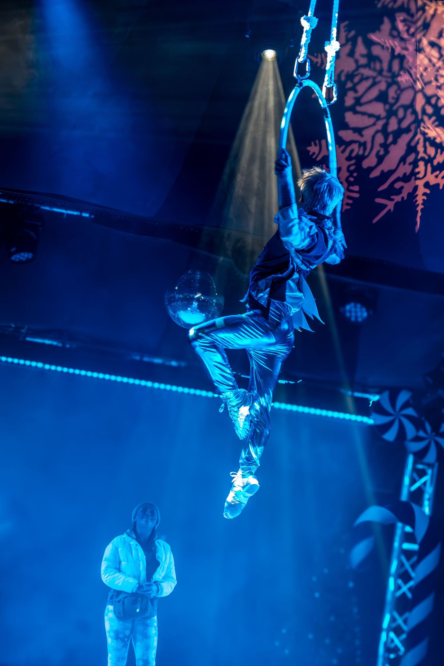 Performers execute aerial stunts with ropes under dramatic blue lighting effects.