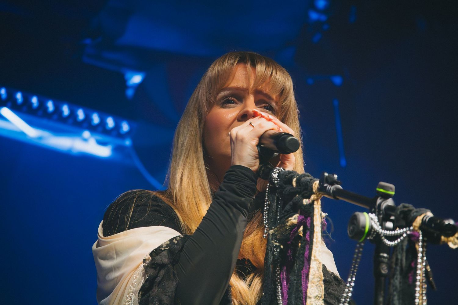 Concert performance on dark stage with dramatic blue lighting and fog effects.