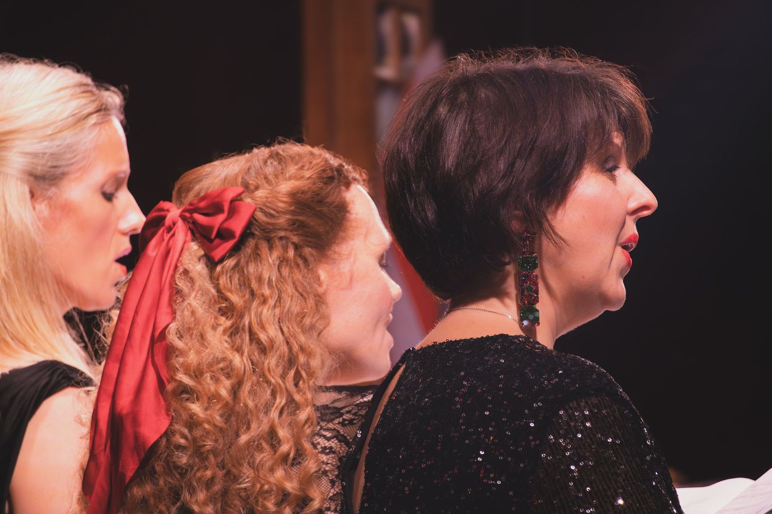 Choir members dressed in formal black attire perform together on stage.
