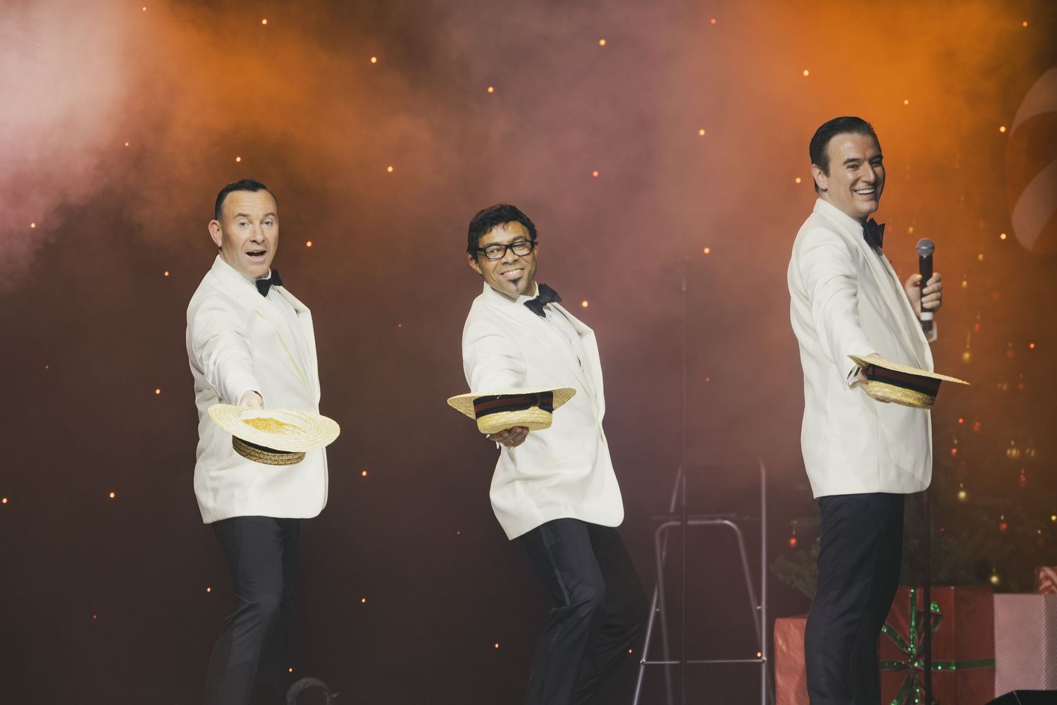 Stage performers in elegant attire dance during festive holiday show.