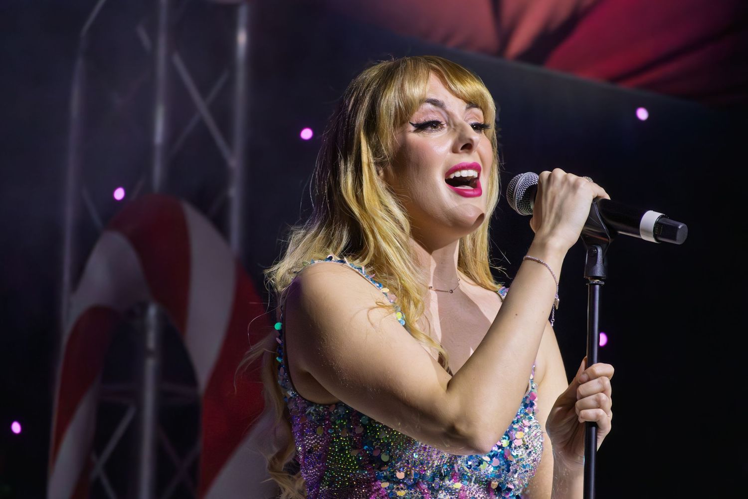 Close-up of concert performance with candy cane striped backdrop and stage lighting.