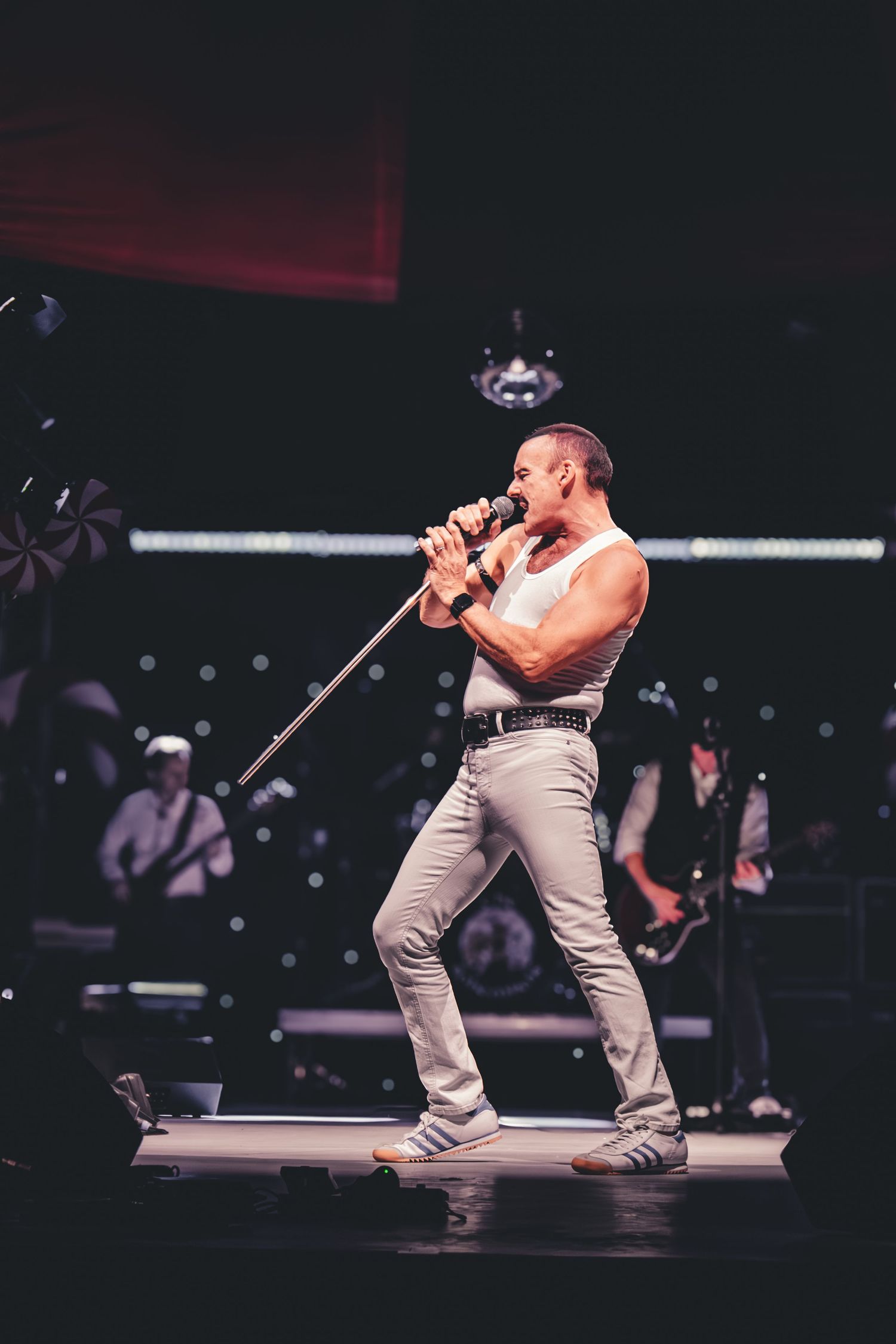 Energetic stage performance with dramatic spotlighting and dark background in concert venue.