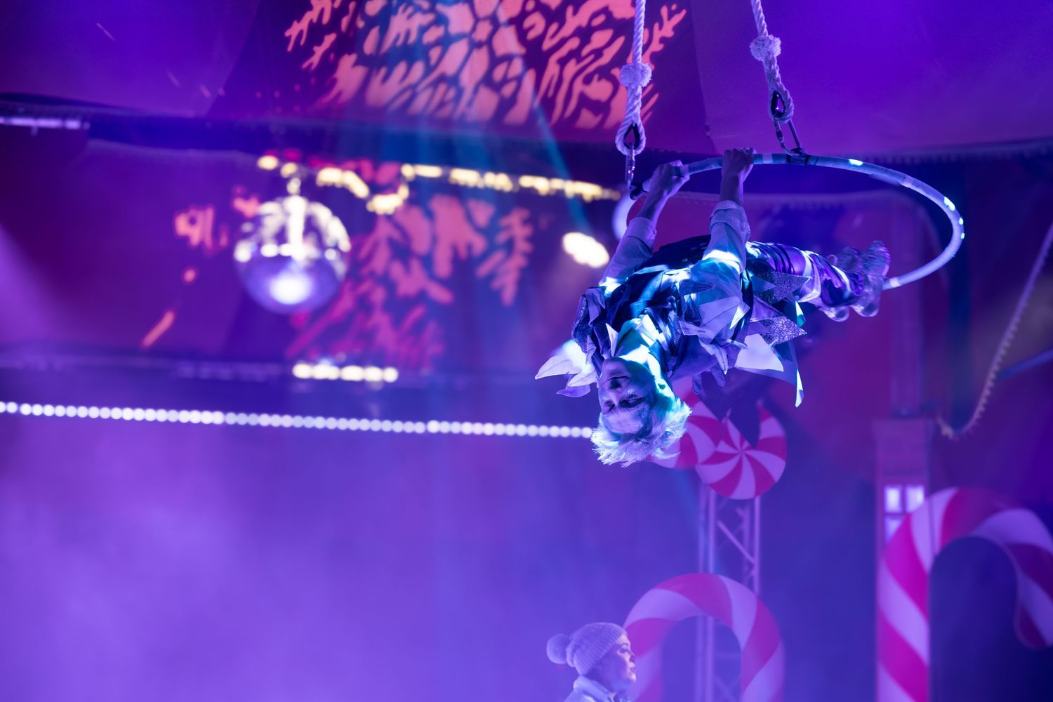 Decorative blue-lit holiday ornaments hang from stage rigging during a performance.