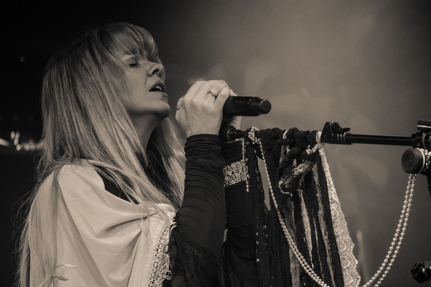 A sepia-toned image shows a singer performing with intensity at a concert venue.