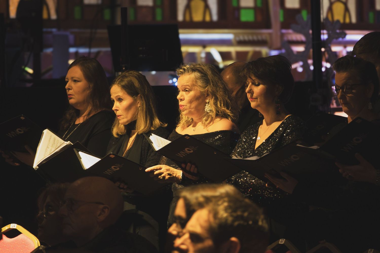 Theater audience members watch a performance in a darkened auditorium.