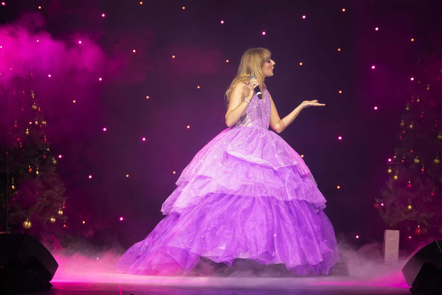 Dramatic performance in flowing purple ballgown against starlit stage backdrop.