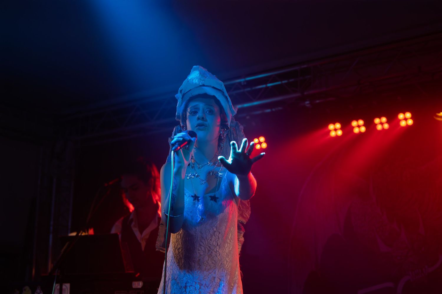 Concert performer singing on stage illuminated by dramatic blue and red lighting during a live music show.