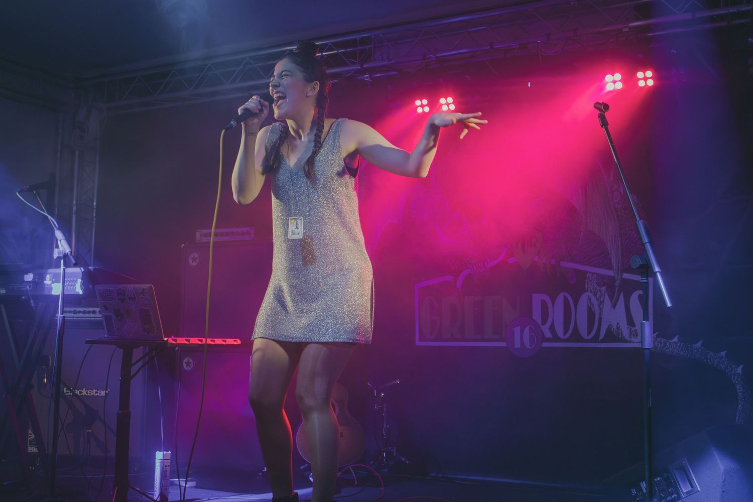 Singer performing on stage illuminated by vibrant magenta lighting during a live concert.
