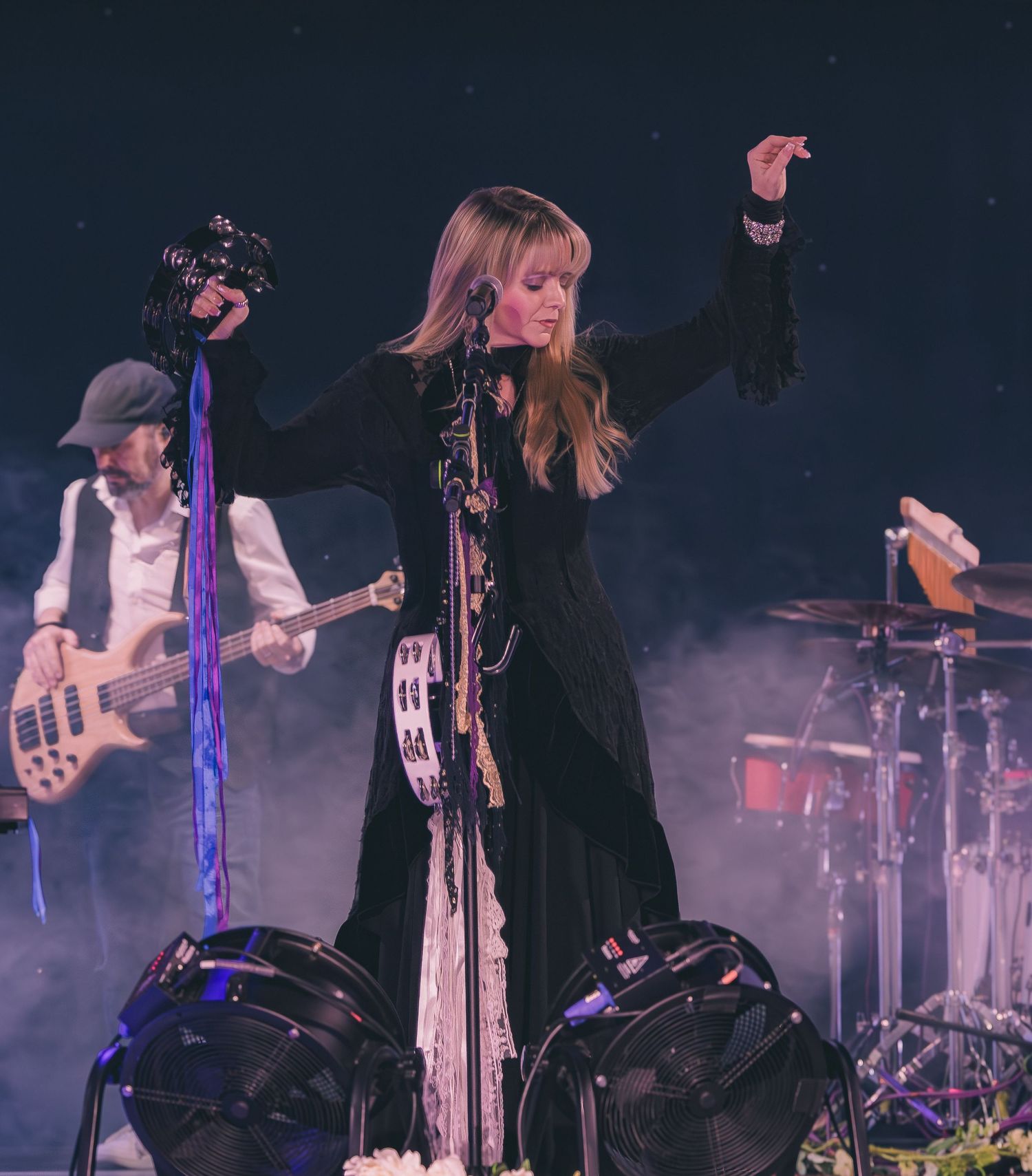 Band performs on smoky concert stage with blue lighting and multiple instruments.