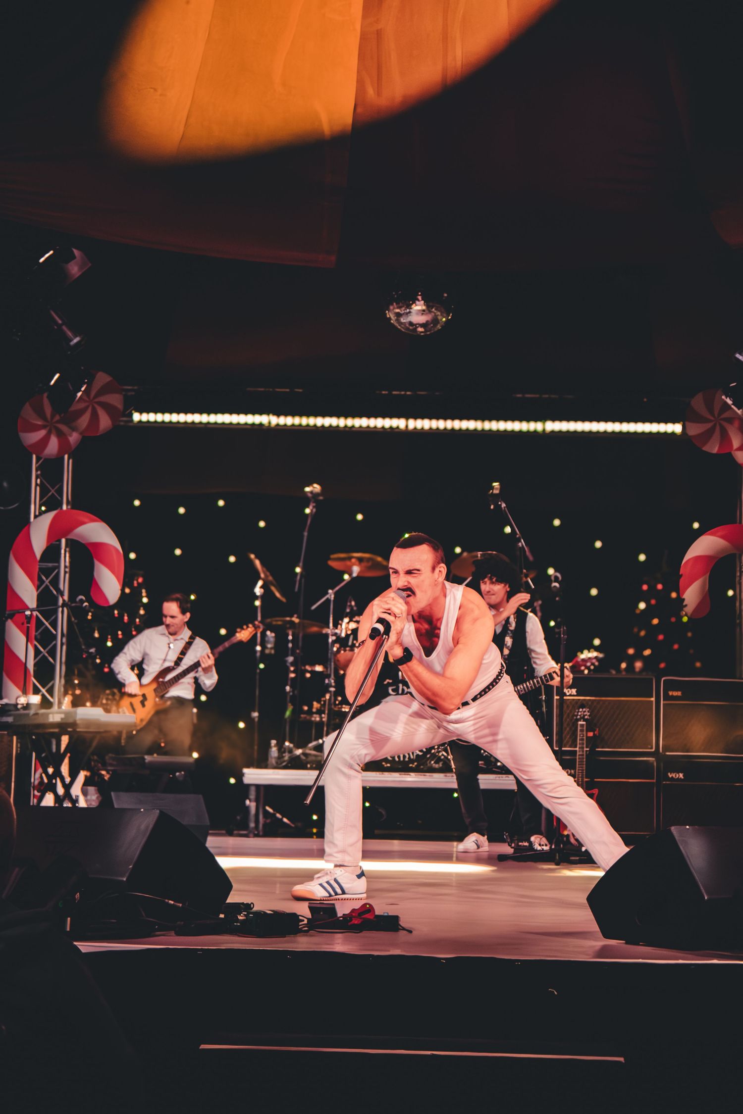 Concert stage with orange lighting showing performers in dynamic poses during show.
