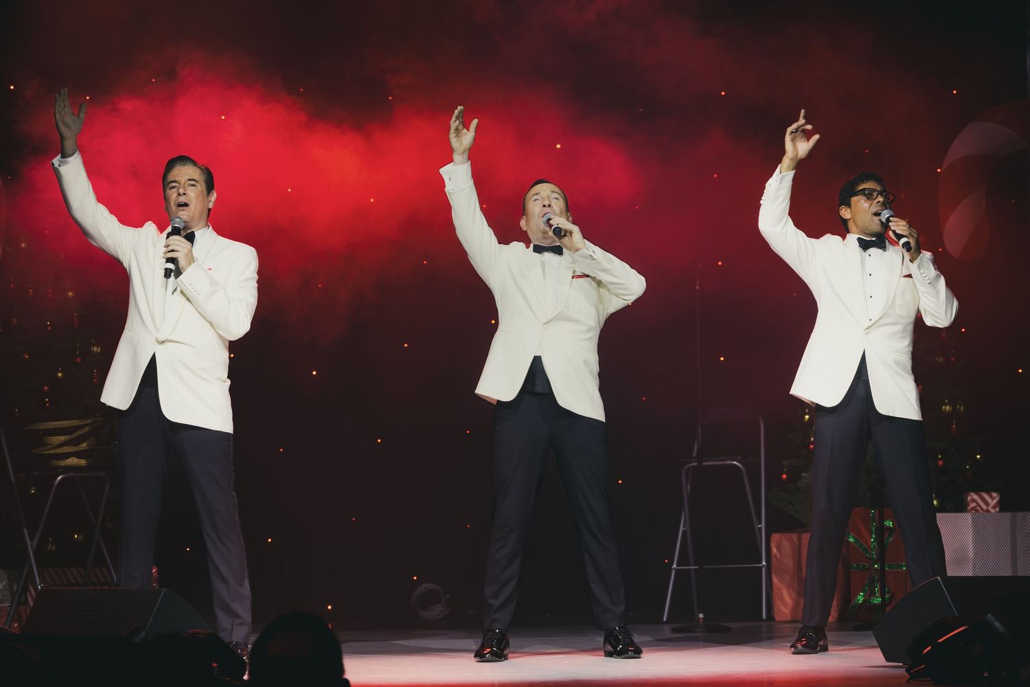 Dynamic stage performance with dramatic red lighting and white-suited entertainer.