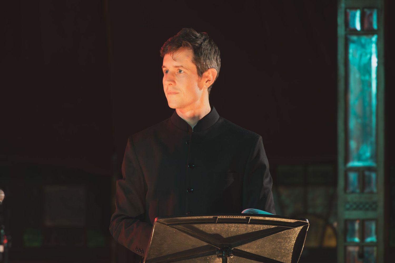 Stage performers illuminated by teal lighting during an evening concert.