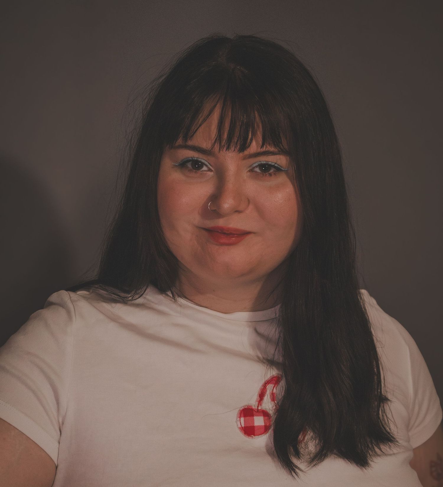 Person with dark bangs and white t-shirt poses in a series of casual selfie-style photos against a dark background.