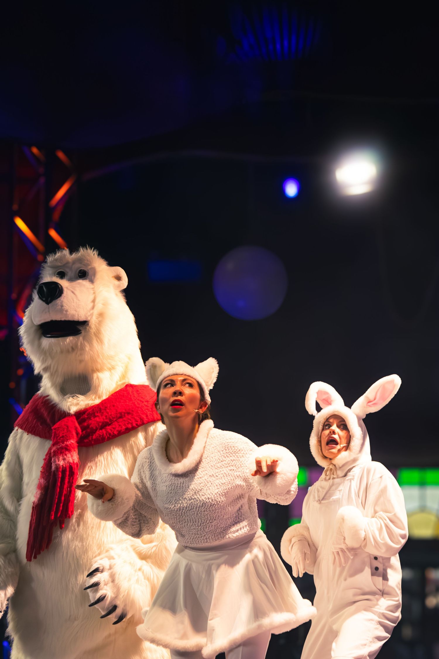 Performers in polar bear and bunny costumes interact during a winter-themed stage show.