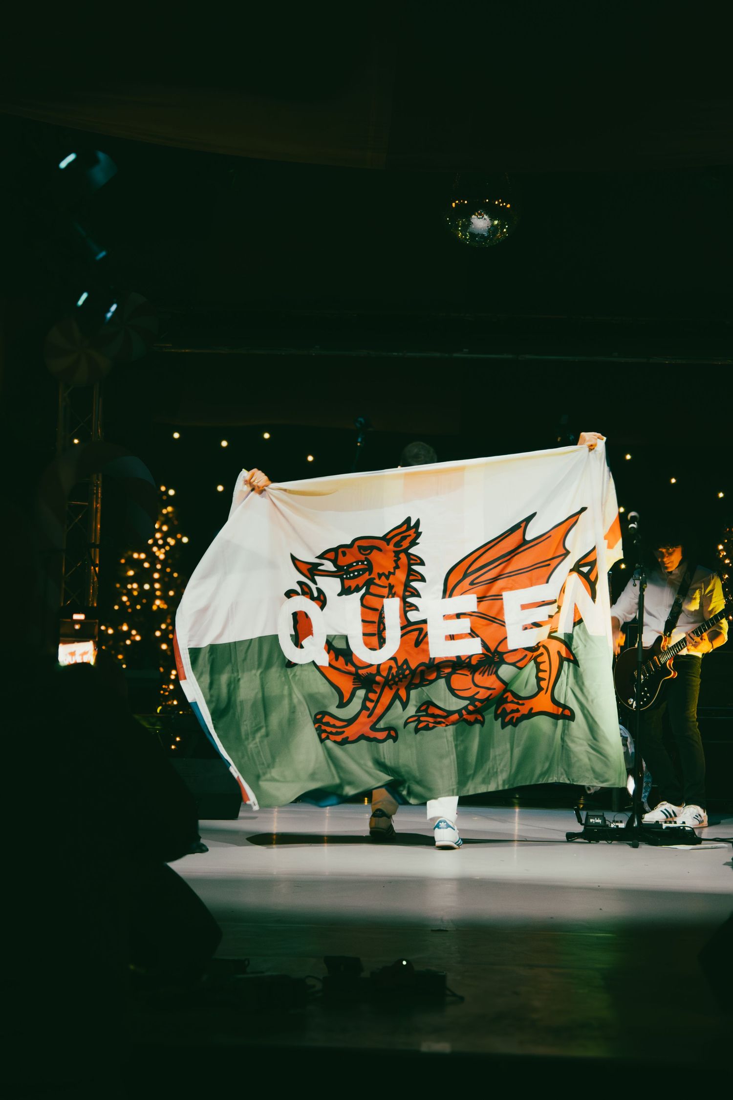Welsh flag displayed on stage during performance with red dragon emblem visible.