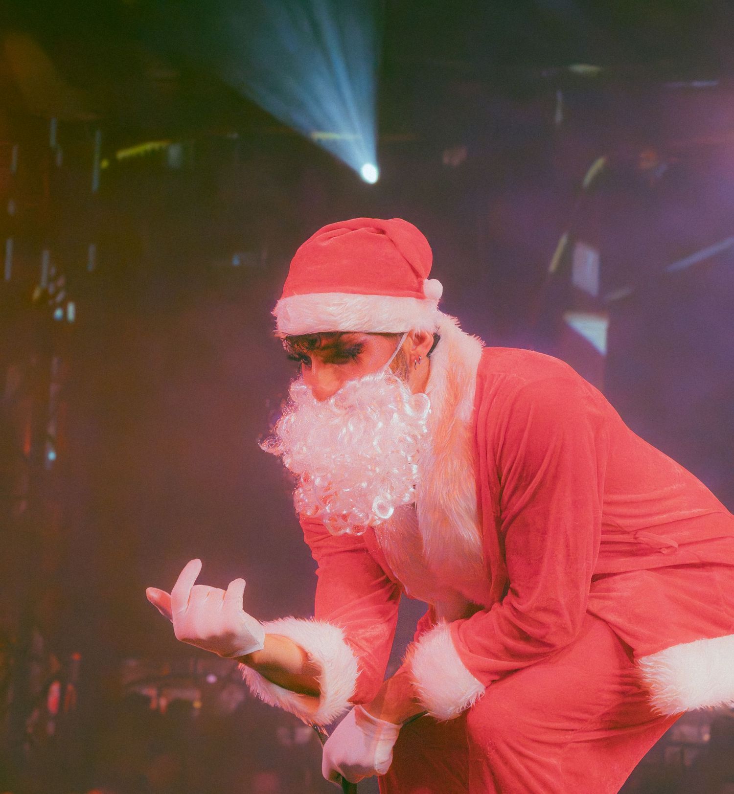 Performer in red outfit and white beard dancing energetically on stage during a festive show.