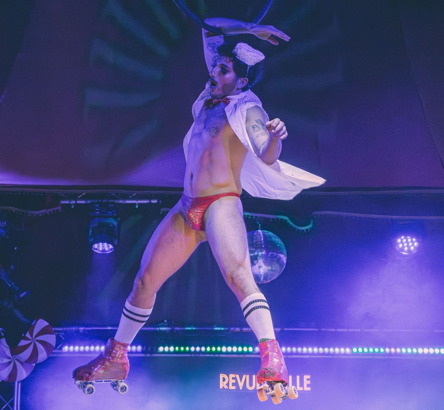 Roller skater performing on stage with dramatic blue lighting and theatrical effects.