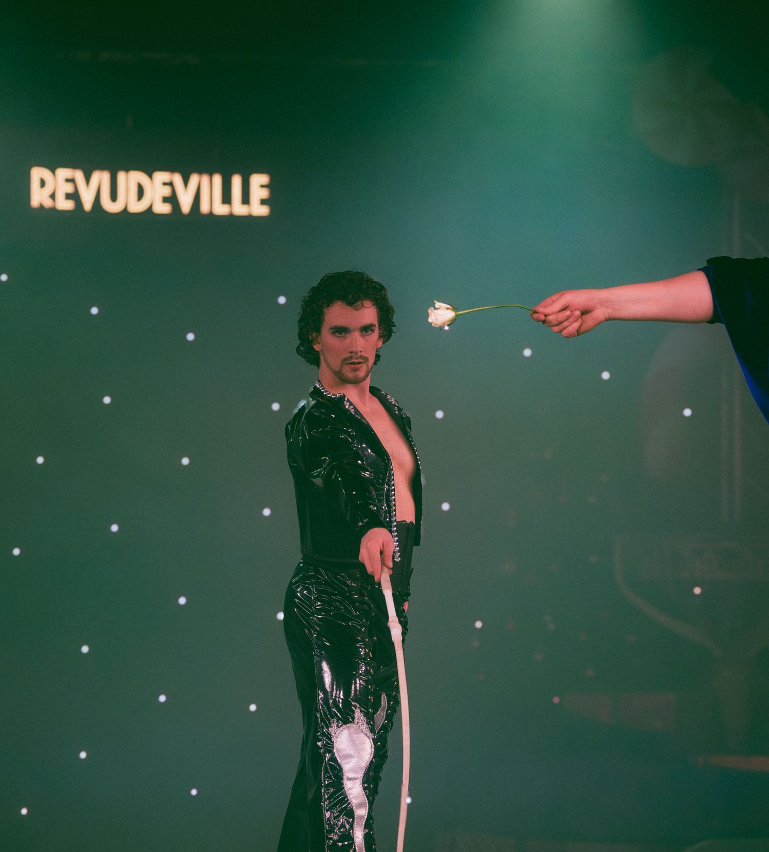 Stage performance at Revudeville with dramatic green lighting and starry backdrop.
