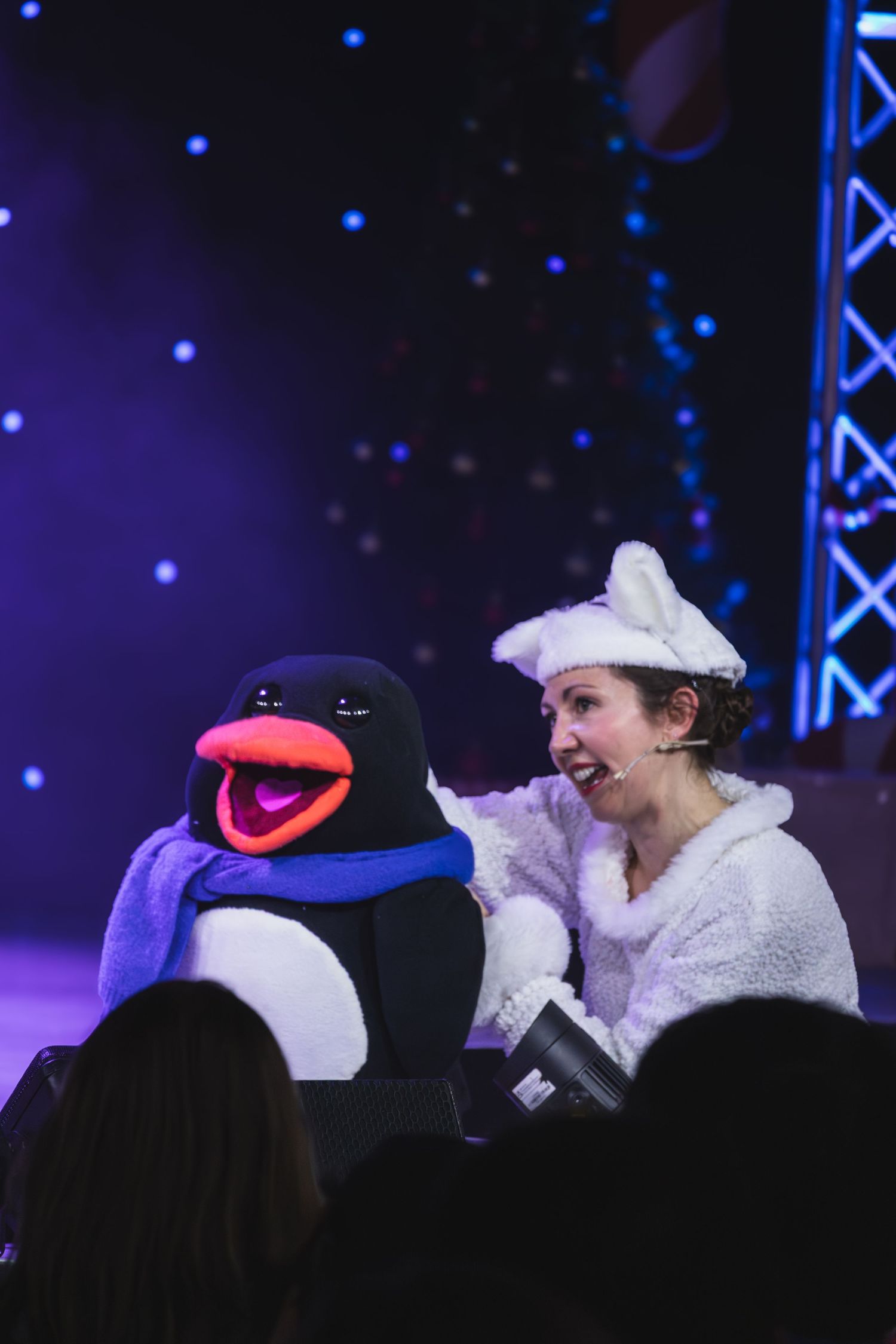 Performers with puppet characters interact playfully against a starlit blue backdrop.