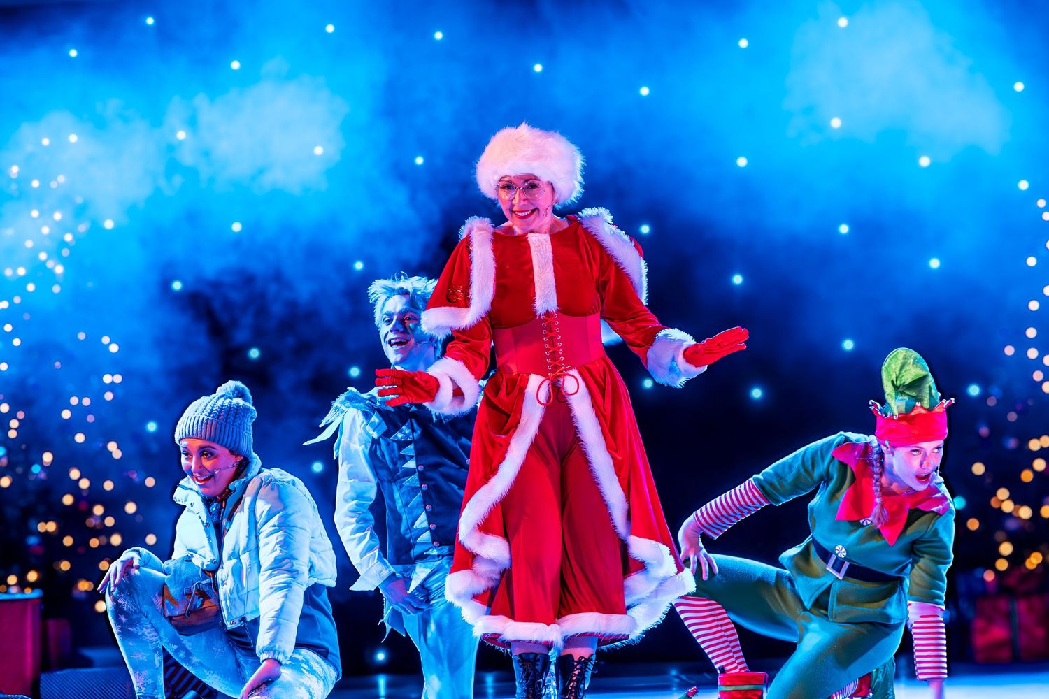 Dancers in colorful winter costumes perform around a central figure in a Santa suit.