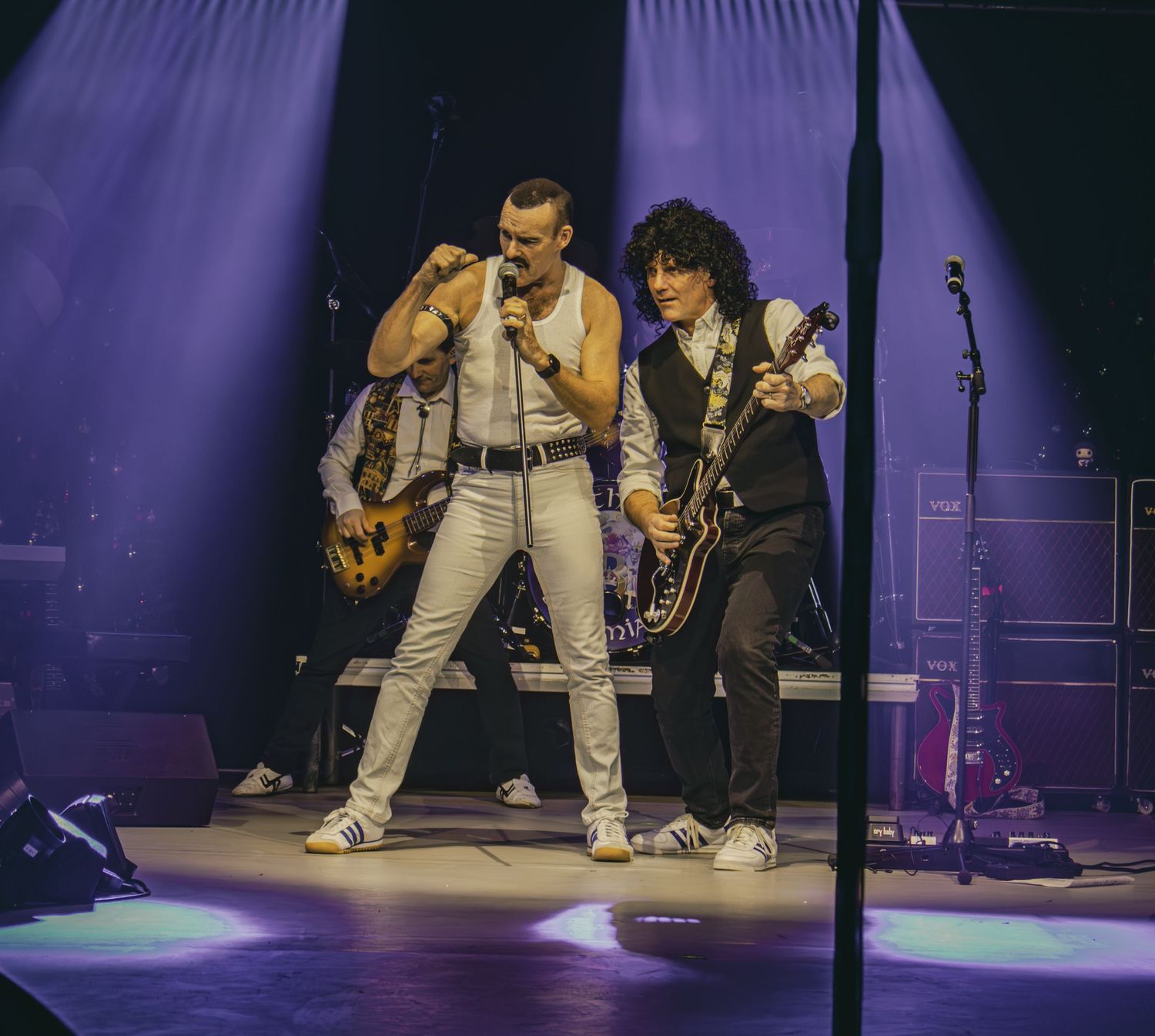 Performers in white outfits dancing energetically on stage during live show.