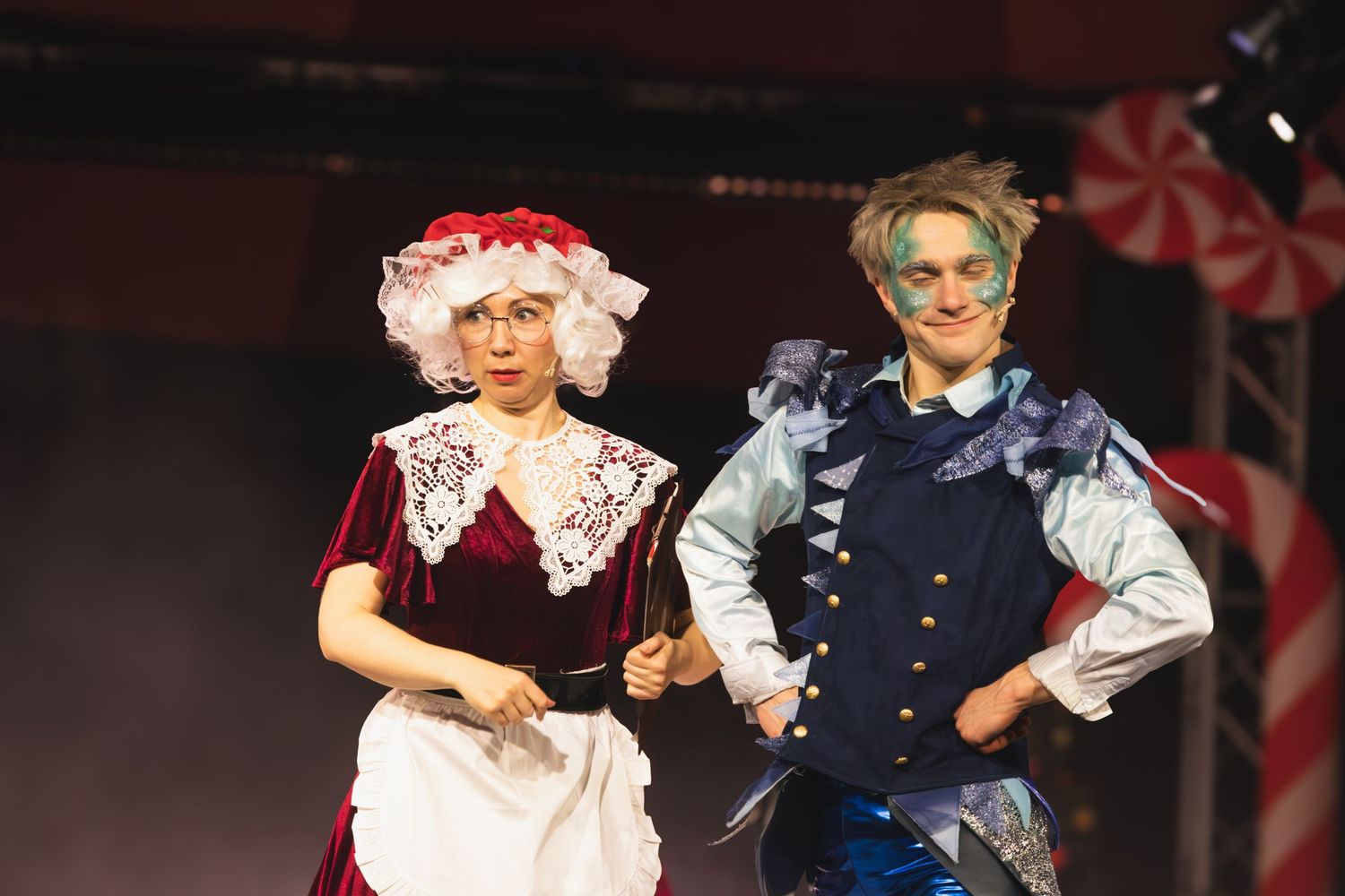Theatrical performers in period costumes interact during a dramatic stage scene.