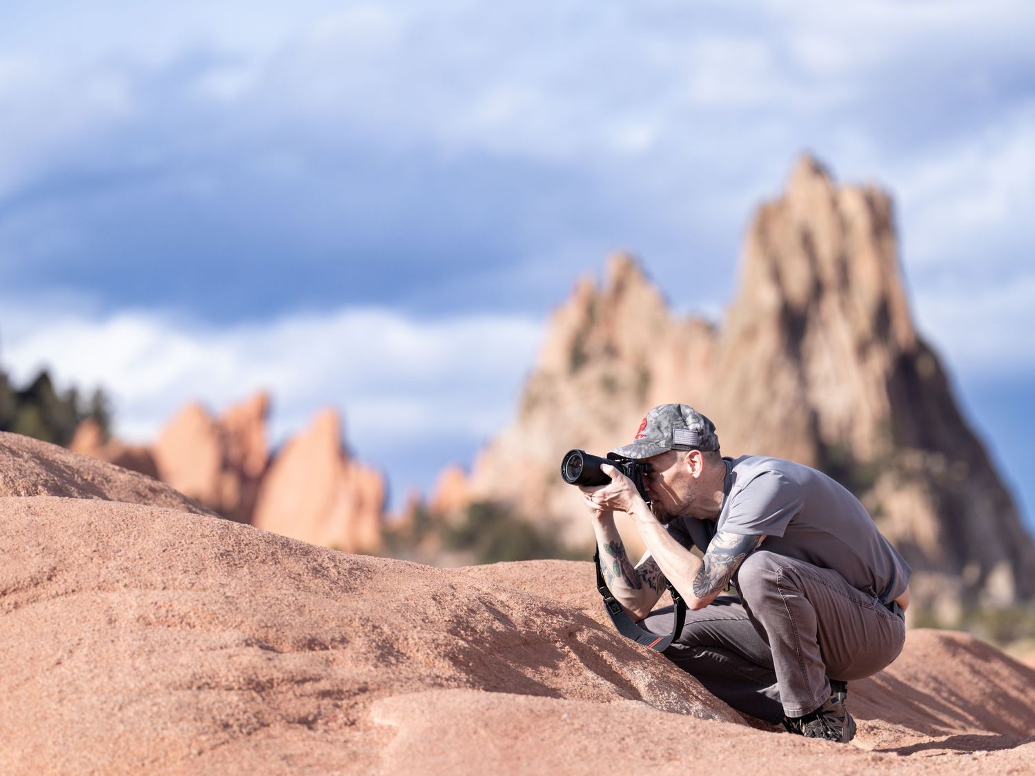 Photographer crouching on red rocks capturing photos at Garden of the Gods.