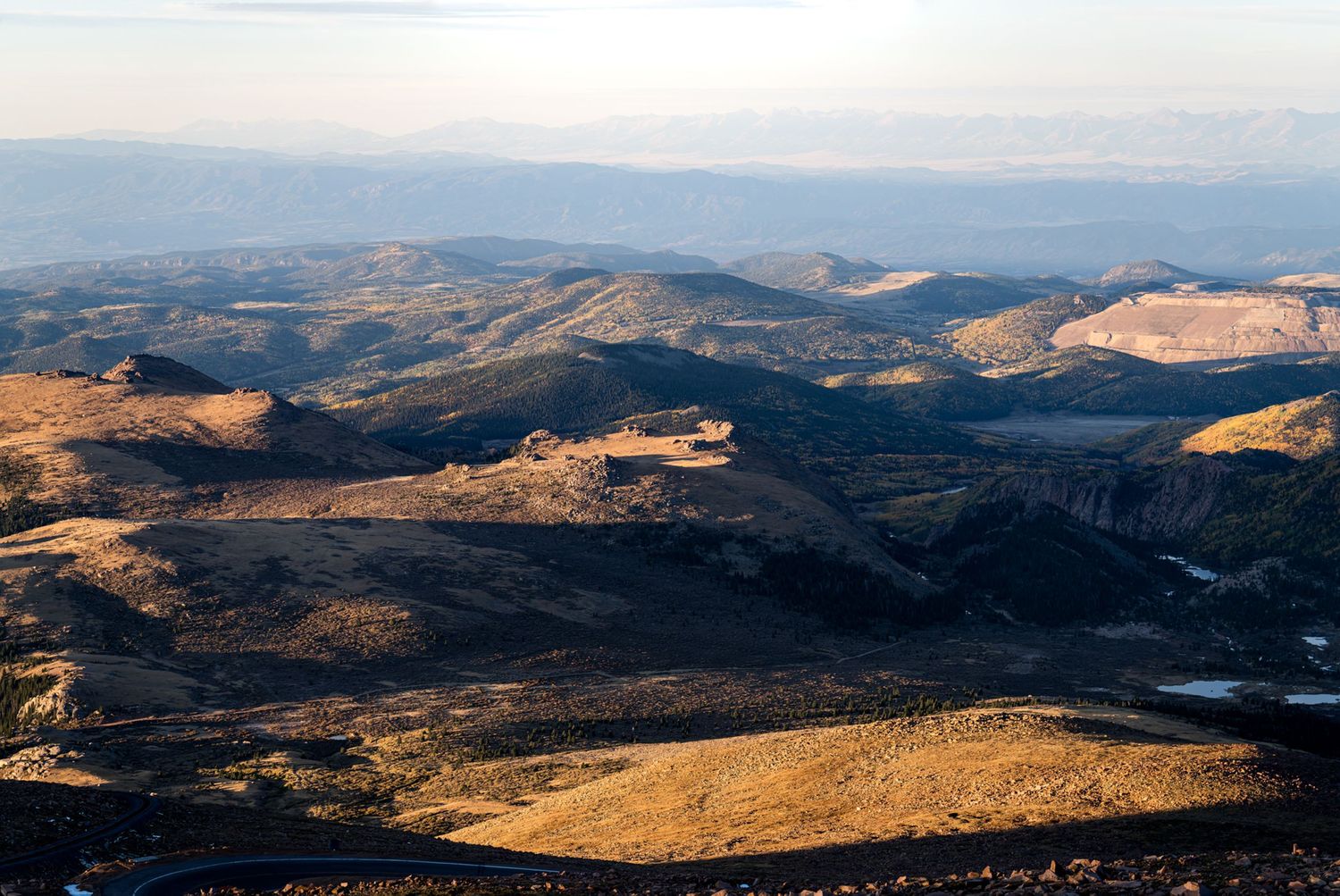 Aerial view of a vast mountainous terrain with valleys and ridges under blue skies.