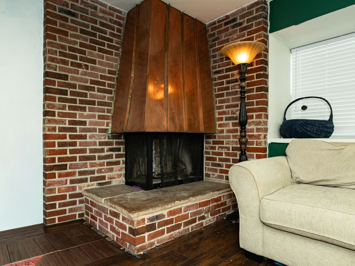 Living room with exposed brick fireplace and cream colored sofa against brick walls.