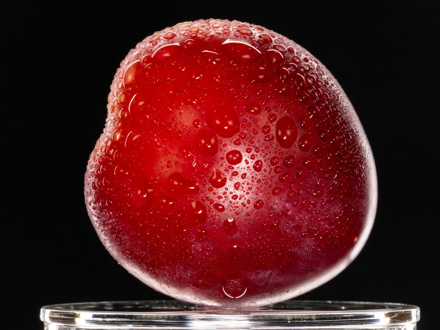 Wet apple slice floating on glass surface with water droplets and dark background.