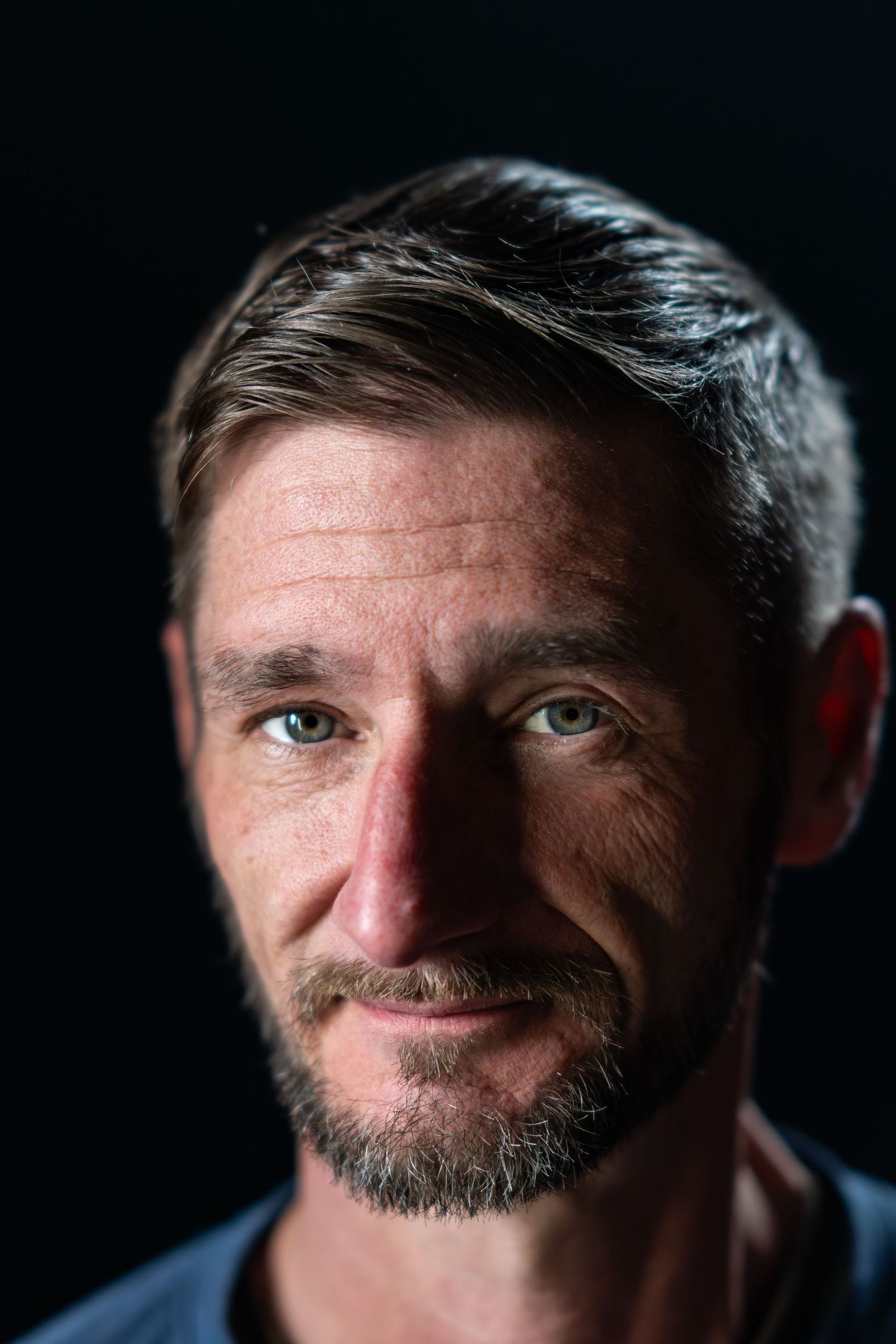 Dramatic close-up portrait against dark background showing eyes and facial features.