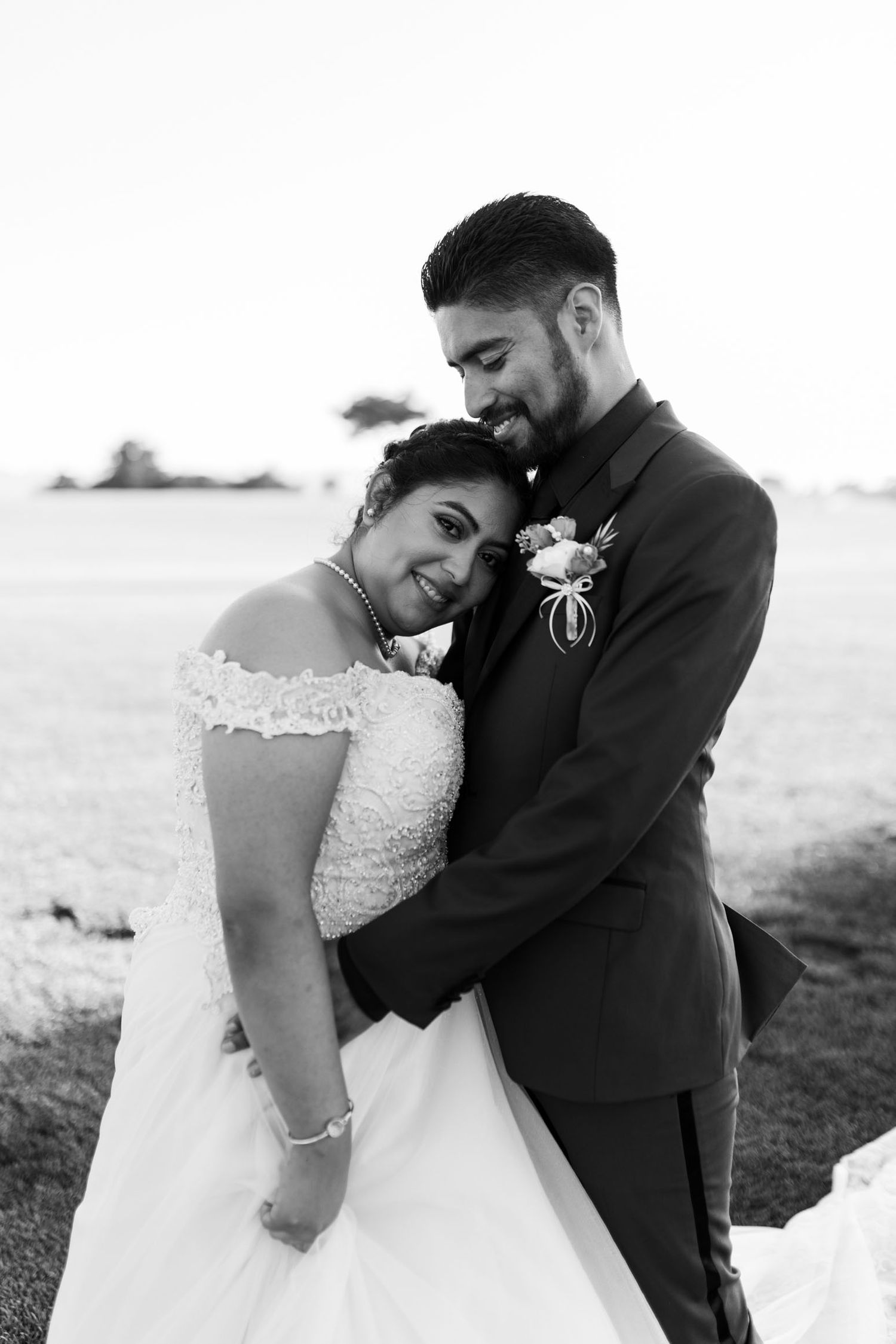 A romantic black and white photo series of a bride and groom embracing outdoors during their wedding celebration.