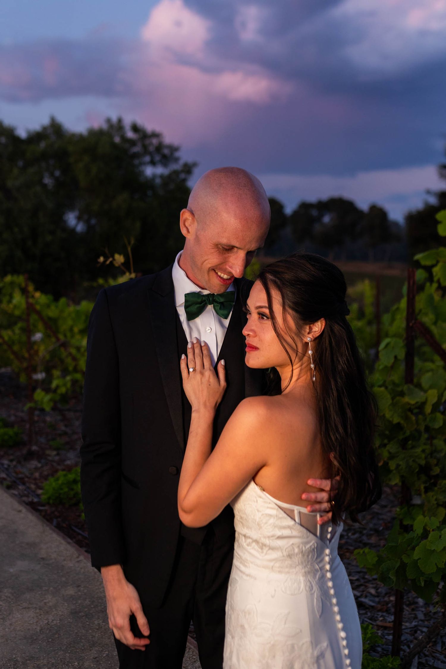 A romantic sunset wedding photoshoot with a couple sharing intimate moments in a vineyard setting.