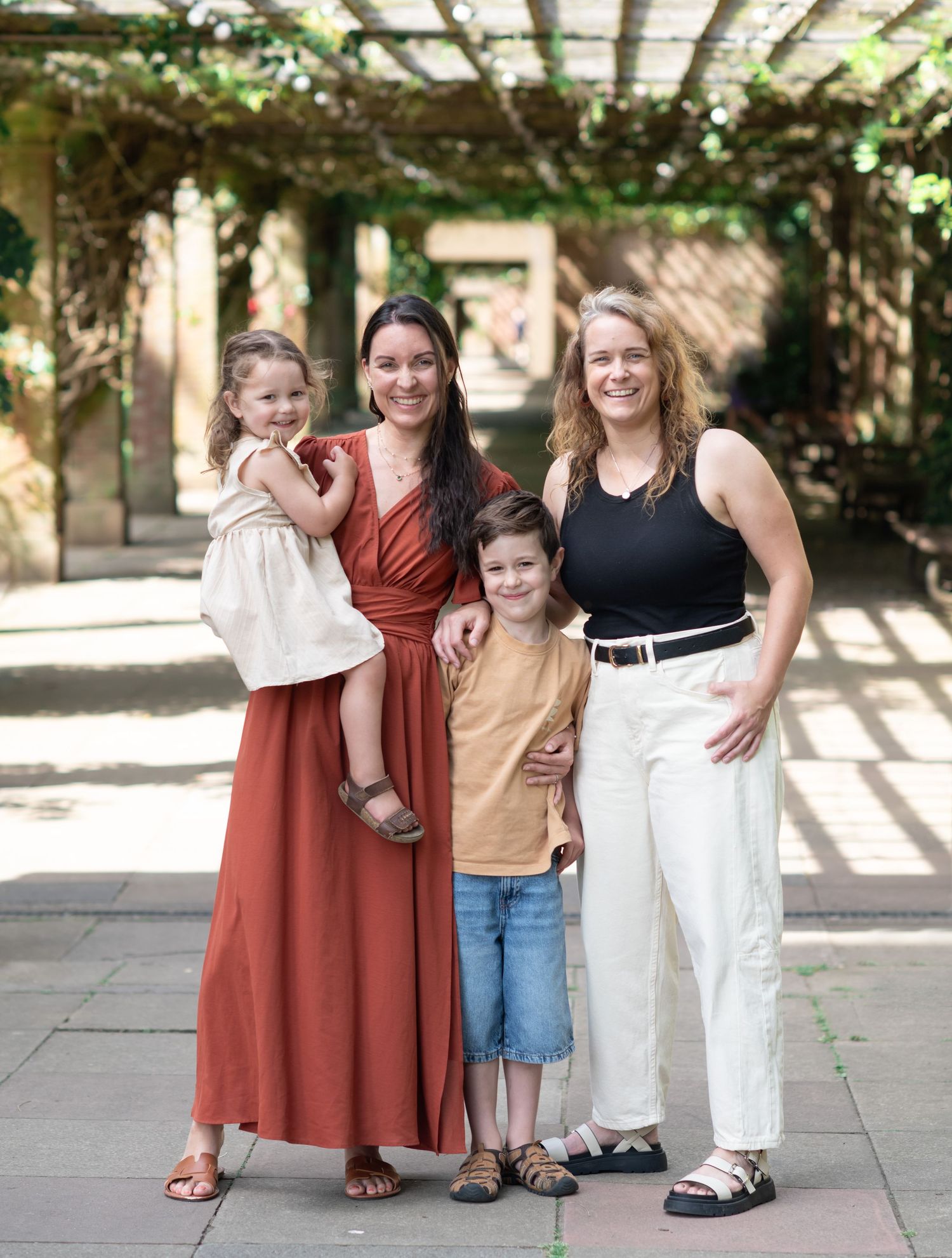 A family standing together on a stone patio with arches at Valley Garens in Harrogate and natural light filtering through overhead.