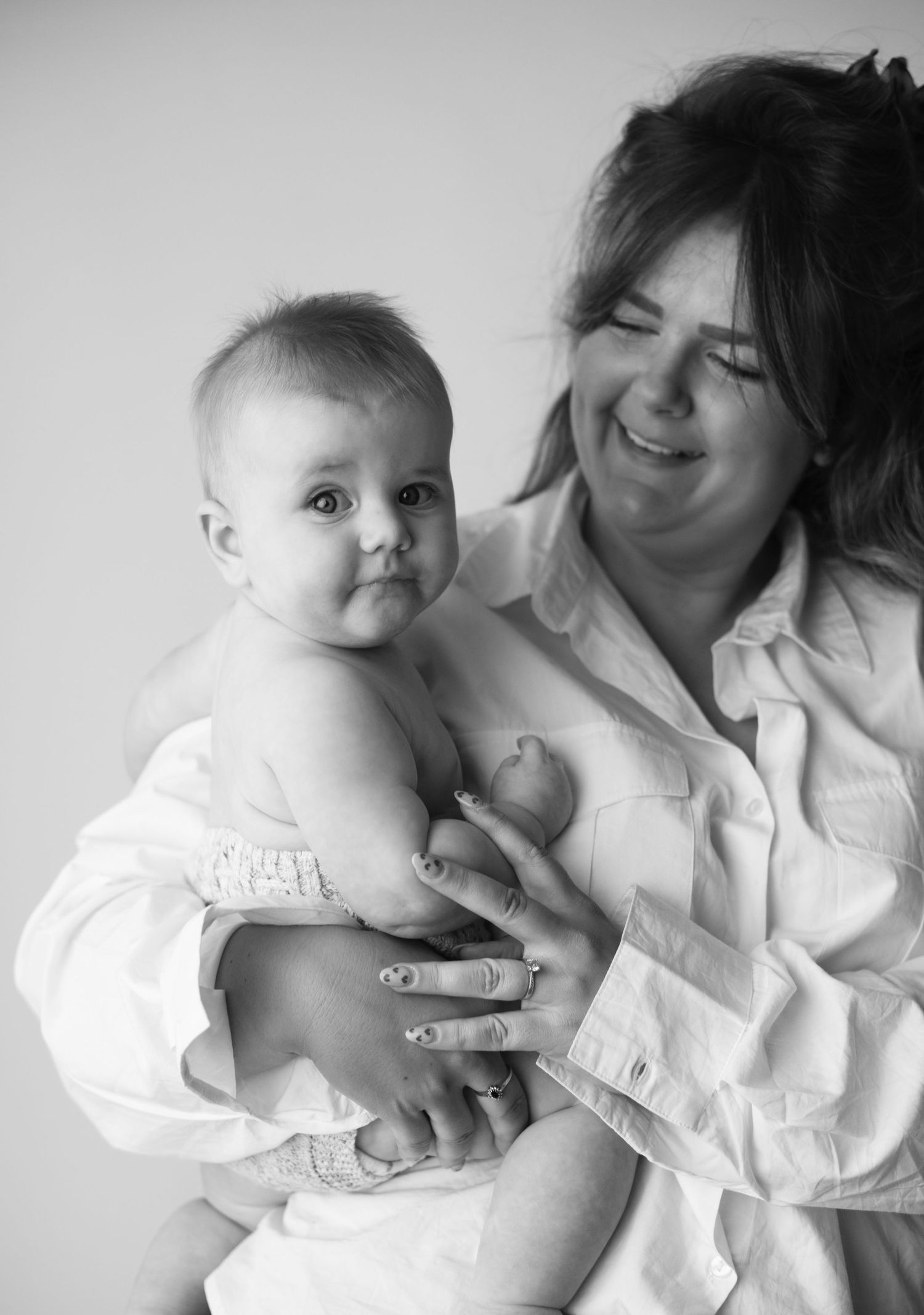 A tender black and white photo series showing intimate moments between mum and baby in matching white clothing.