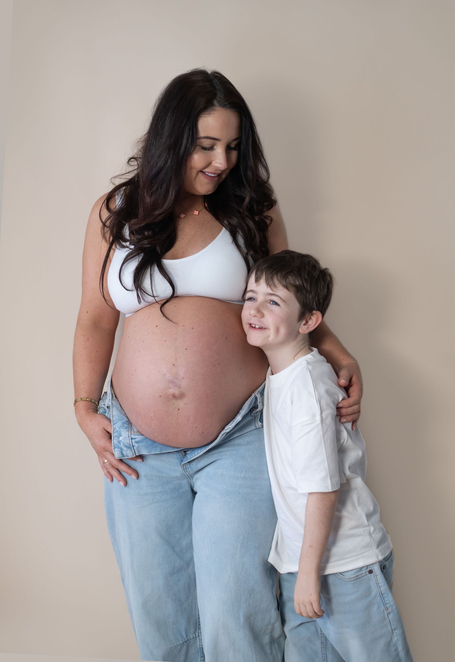 A pregnant mother smiling at her son in a simple maternity photo.