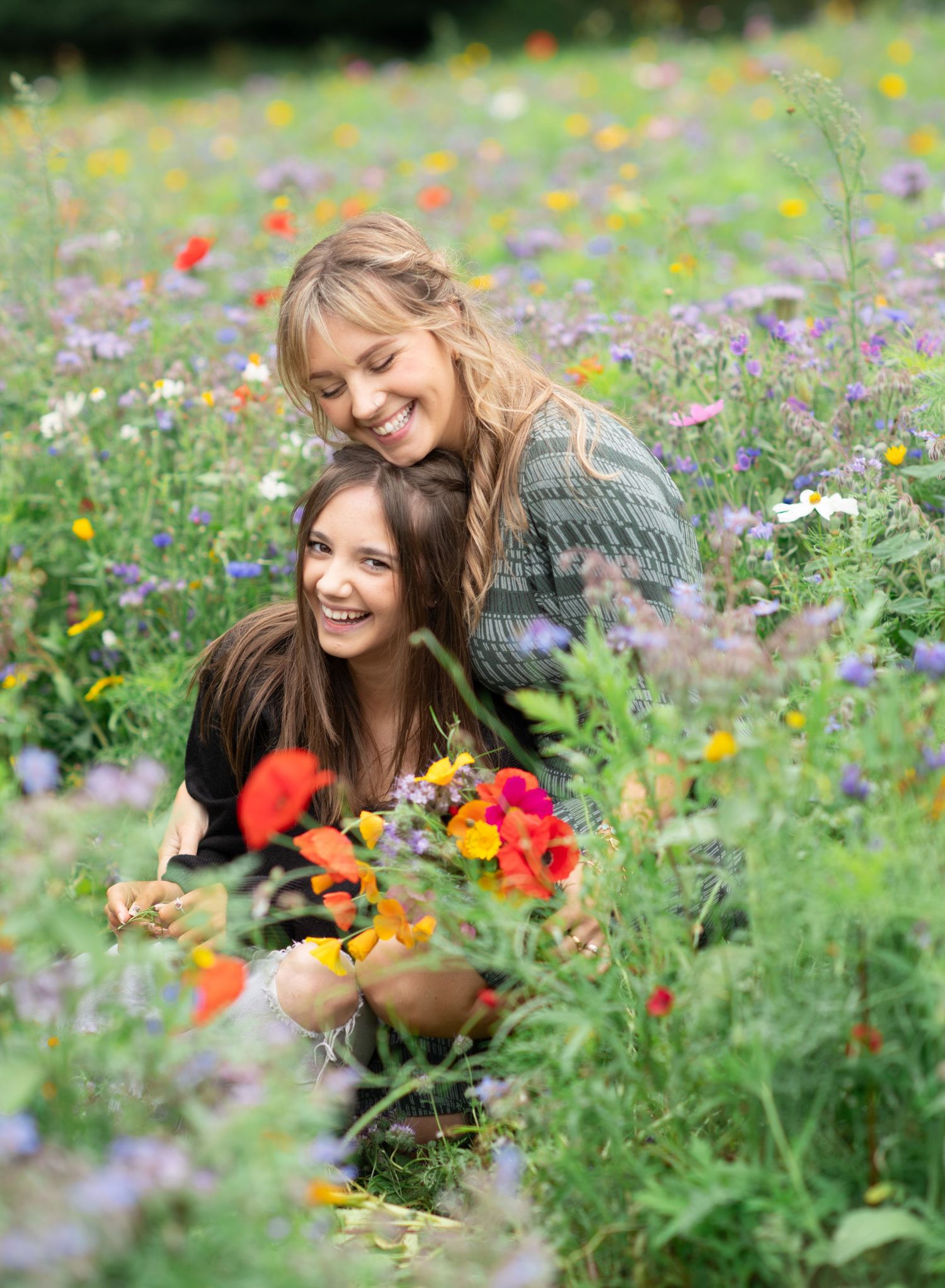 Mother and daugther enjoying a sunny day together in a vibrant wildflower meadow filled with colorful blooms and greenery.