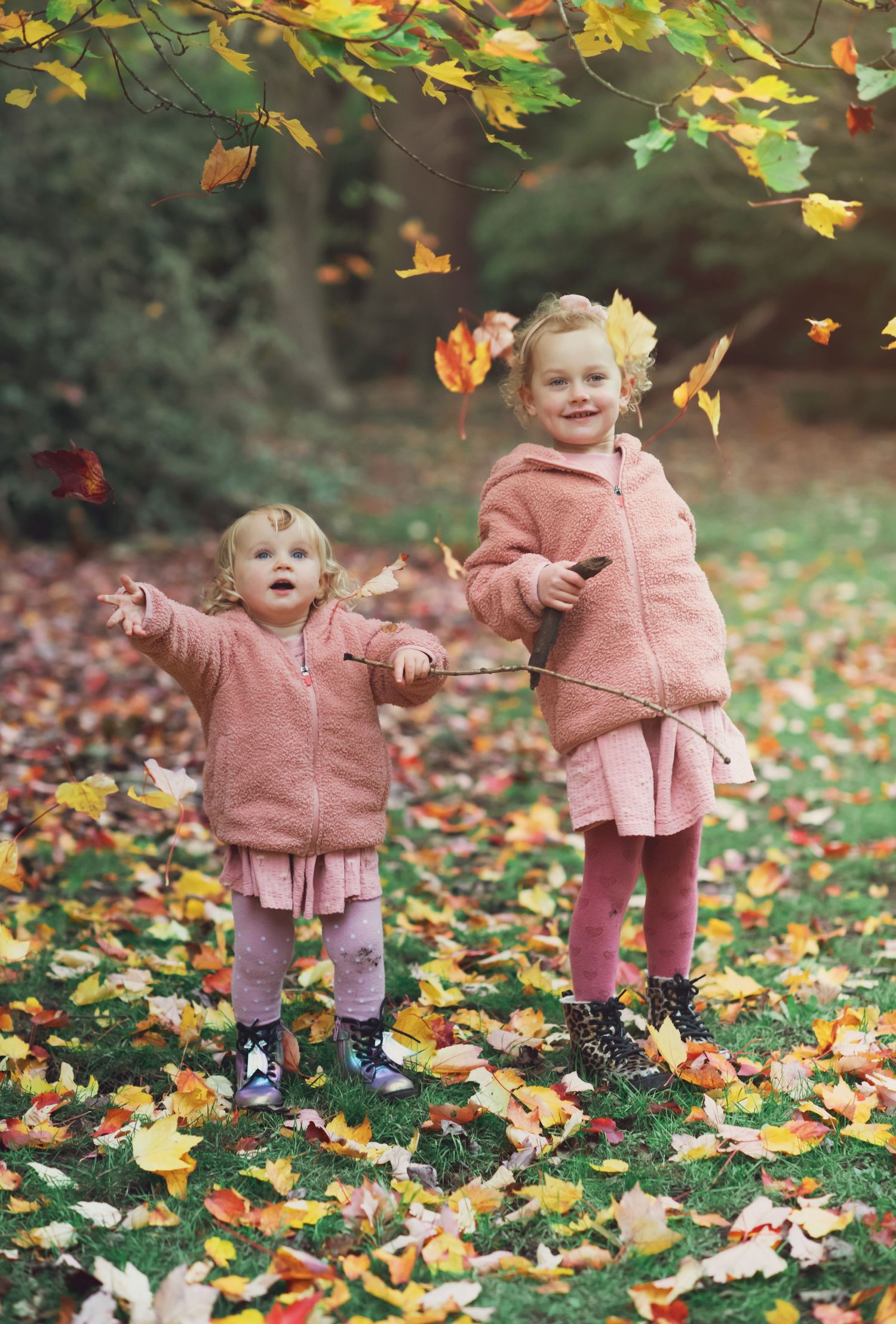Two sisters throwing Autumn leaves into the air at Golden Acre Park Leeds