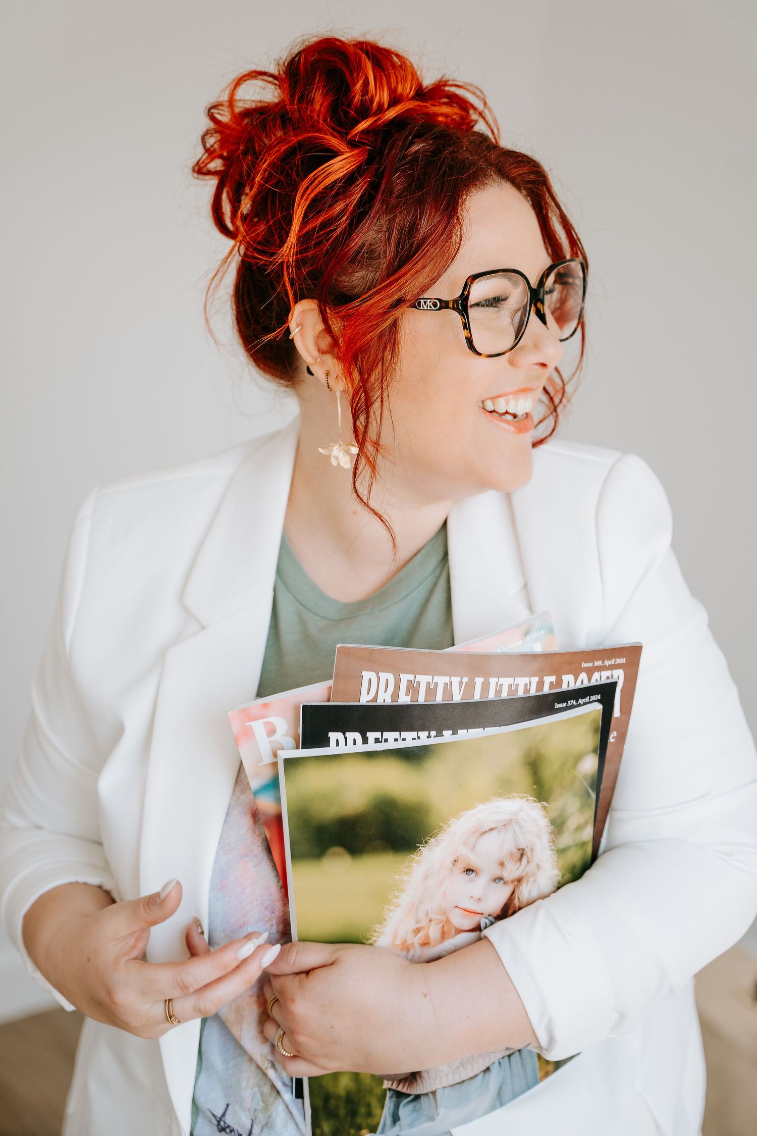 A series of three photos showing someone with vibrant red hair wearing glasses and a white blazer holding photo prints.