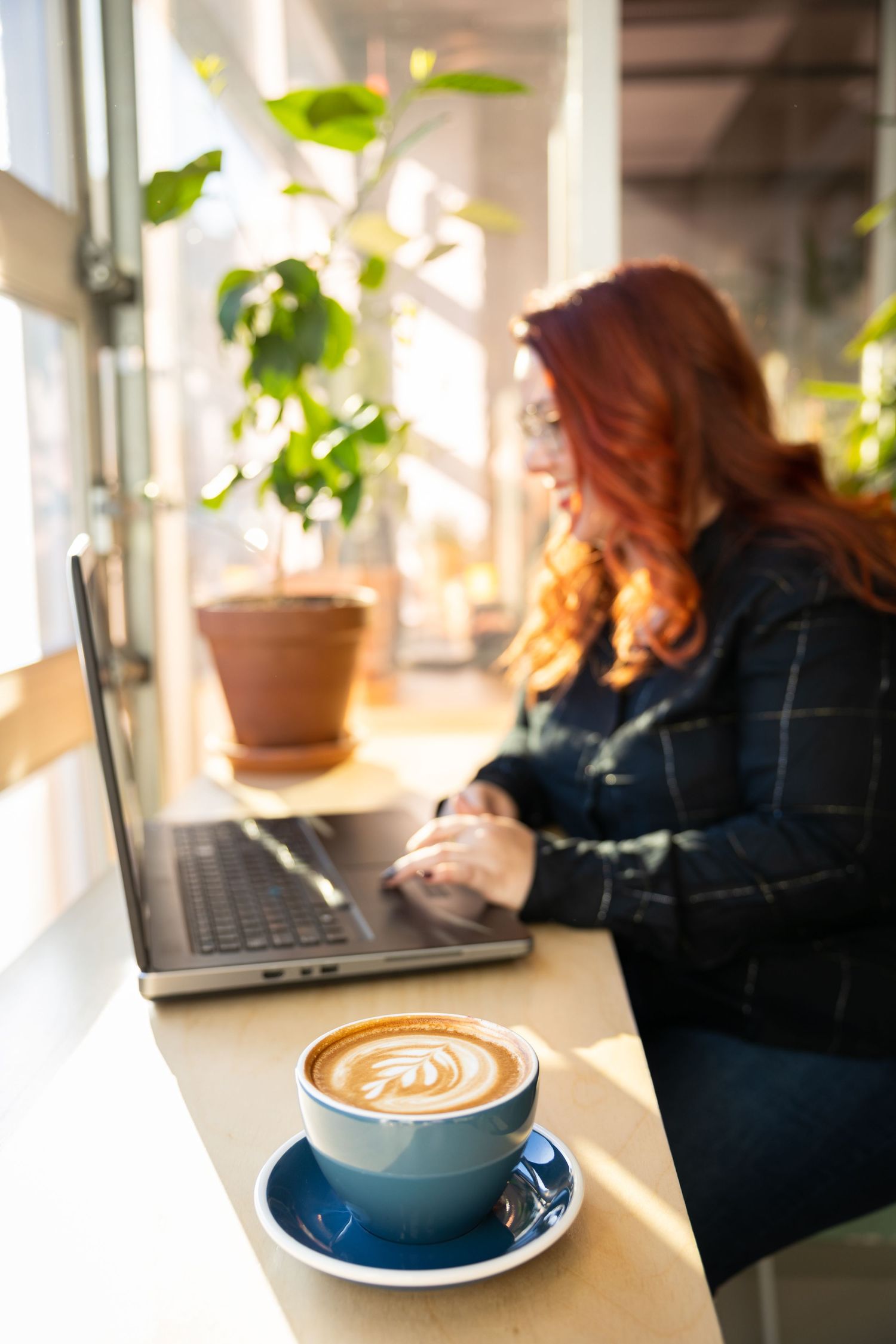 A series of coffee cups with latte art on a windowsill, with natural light streaming in.
