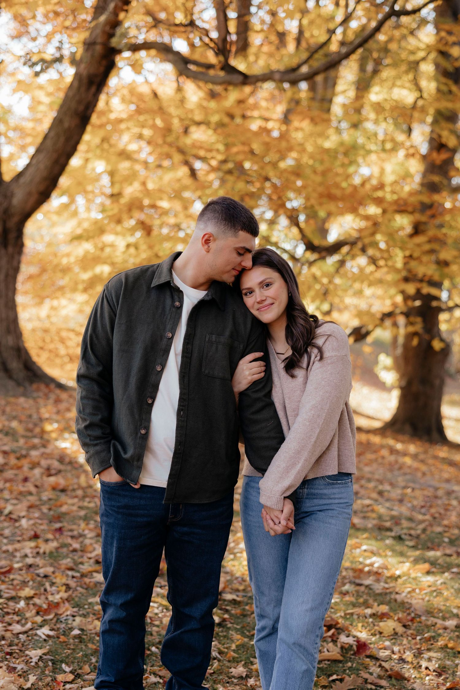 Romantic autumn photoshoot with couple laughing under golden trees at Highland Park