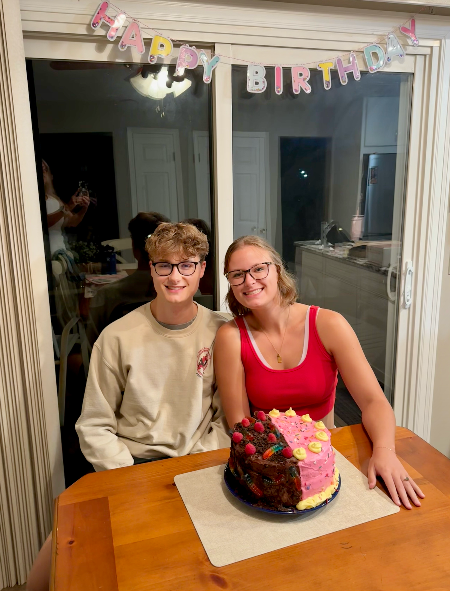 A birthday celebration with colorful bunting decorations and chocolate cake on a wooden dining table.
