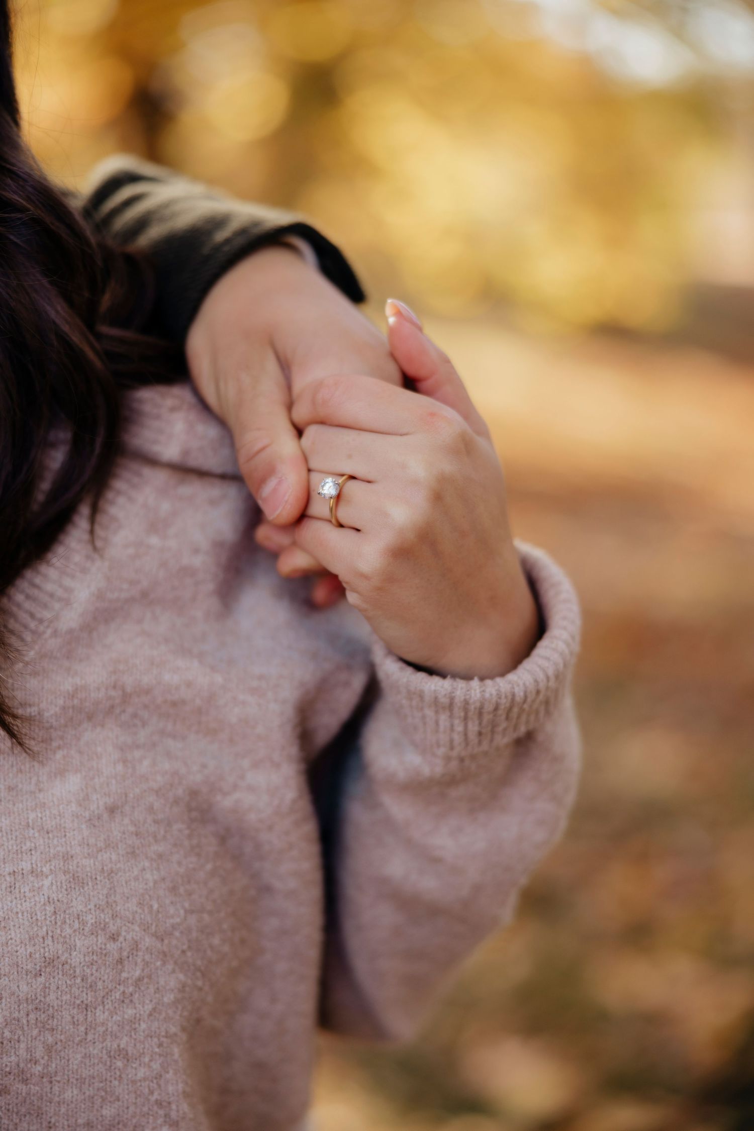 Close-up of engagement ring on hand against yellow autumn background at Highland park, Rochester, NY for engagement photos.