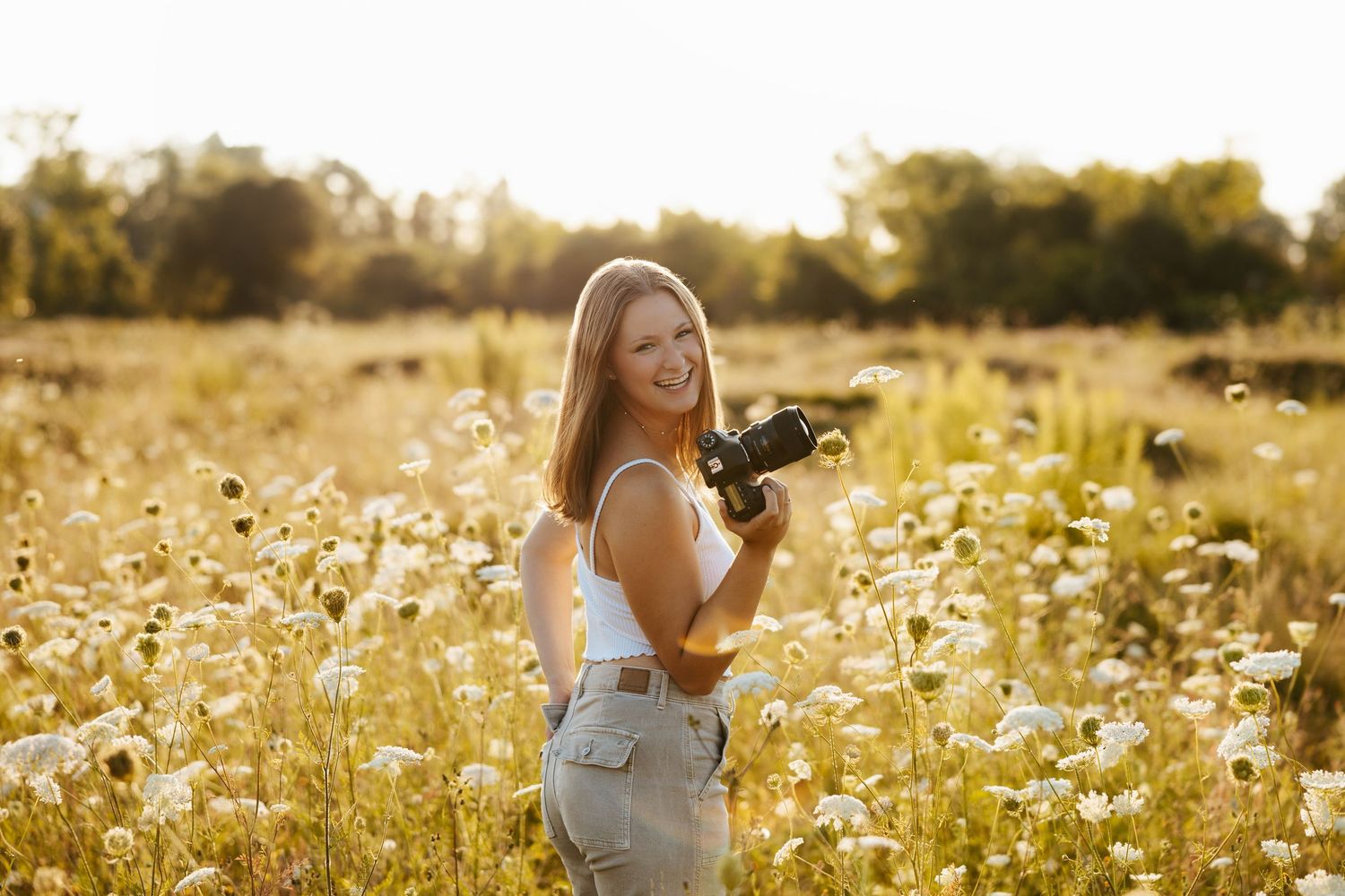 Photographer taking pictures in golden sunlit meadow of wildflowers.